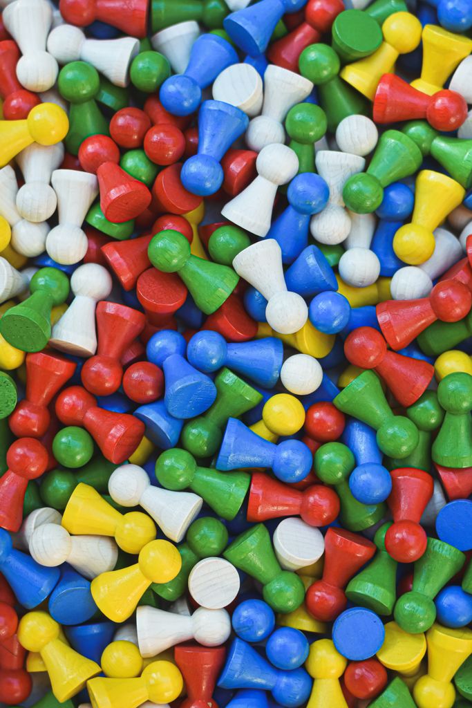 A vibrant collection of multicolored wooden pawn pieces scattered randomly for board games.